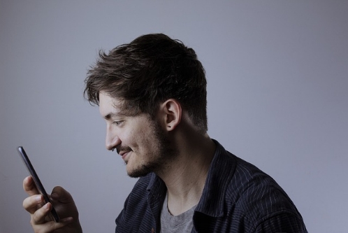 un homme qui souris devant son écran de portable